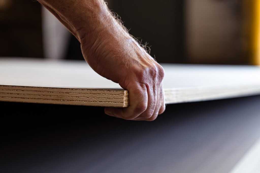 Man's hand lifting plywood