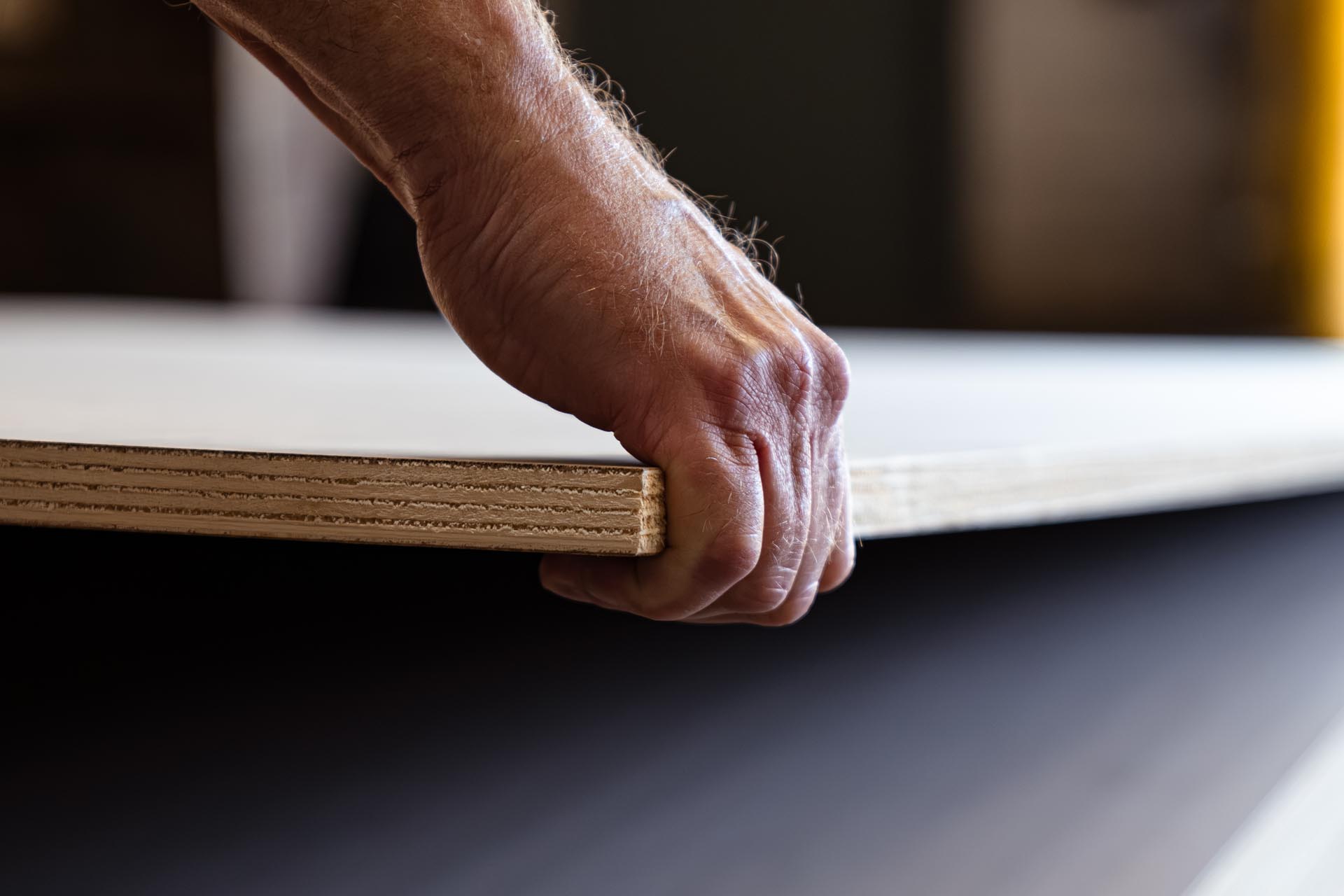 Man's hand lifting plywood