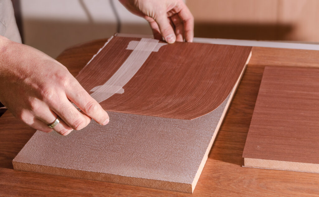 Applying a veneer to a panel of plywood